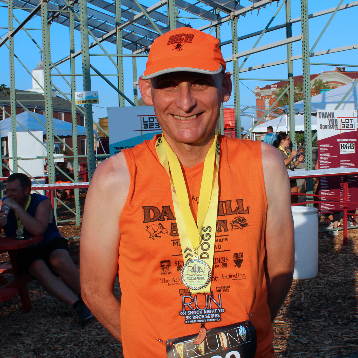 Ian smiling and wearing a finisher medal after running a race. 

