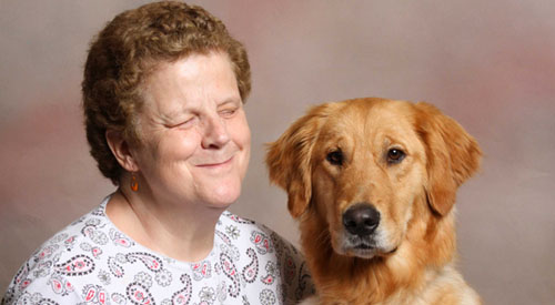 TSE Graduate Mary Anne Lynskey smiles next to her Seeing Eye dog, Faith, a golden retriever.

