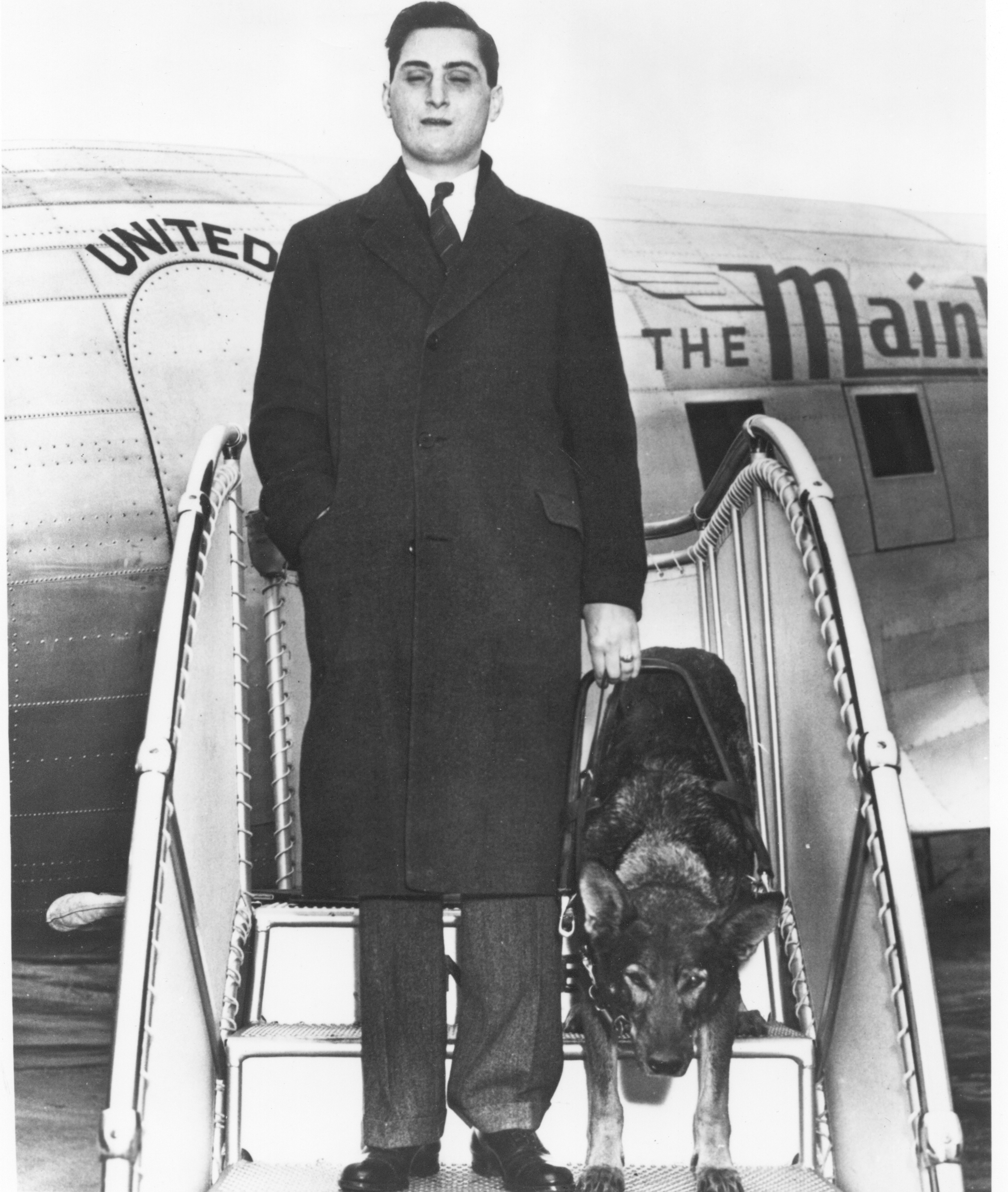 Morris Frank, guided by Buddy, exits a plane.
